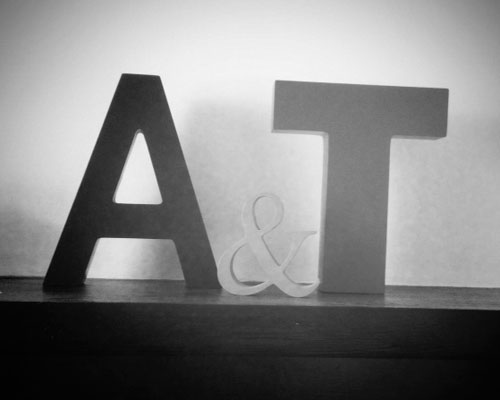 A carved A & T sit on a mantle piece